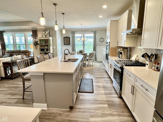 3691 Talmine Ln, Bargersville, IN 46106 - kitchen featuring a sink, wall chimney exhaust hood, stainless steel gas range, a kitchen bar, and light wood-type flooring