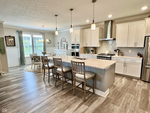 3691 Talmine Ln, Bargersville, IN 46106 - kitchen with wall chimney exhaust hood, crown molding, stainless steel appliances, a center island with sink, and a breakfast bar area