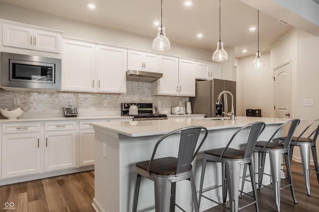 747 Tuxedo Dr, Westfield, IN 46074 - kitchen featuring appliances with stainless steel finishes, under cabinet range hood, dark wood-style floors, an island with sink, and white cabinets