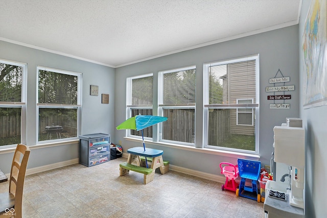 rec room with crown molding, a textured ceiling, and baseboards