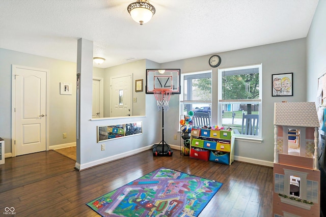 rec room featuring baseboards, hardwood / wood-style flooring, and a textured ceiling