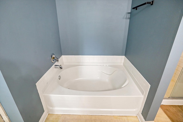 full bath featuring a garden tub and baseboards