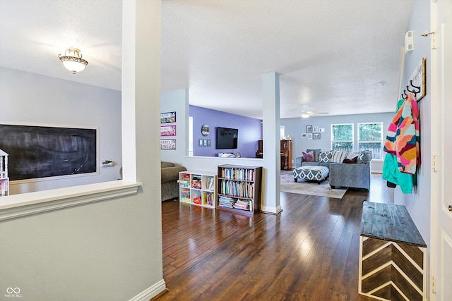 living room with wood finished floors, ceiling fan, baseboards, and a textured ceiling