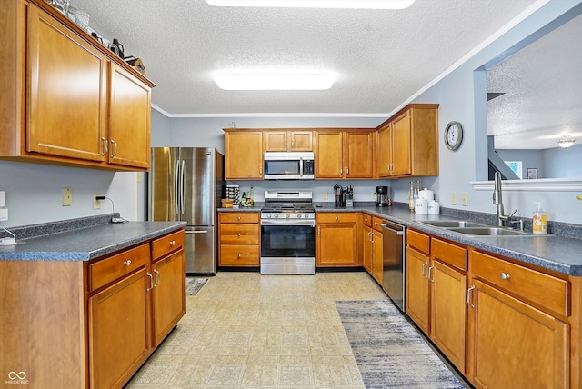 kitchen featuring stainless steel appliances, a sink, a textured ceiling, brown cabinets, and dark countertops