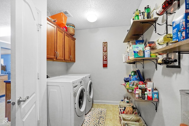 laundry room with washer and dryer, a textured ceiling, cabinet space, and baseboards