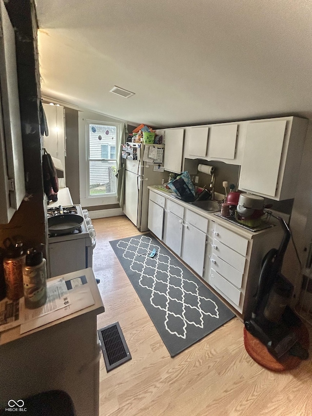 kitchen featuring white appliances, white cabinetry, light wood-style floors, and light countertops