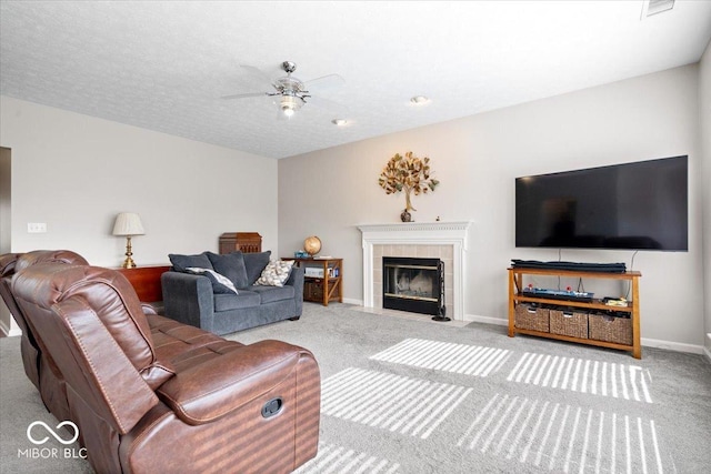 living room featuring carpet flooring, ceiling fan, baseboards, and a tile fireplace