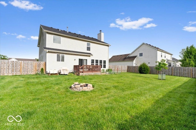 back of property featuring a chimney, a fire pit, and a wooden deck