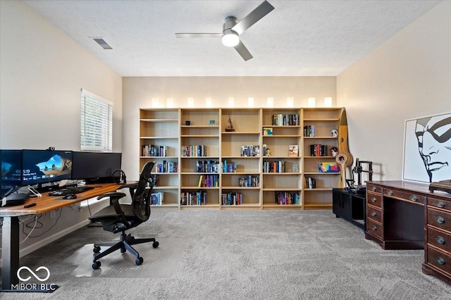 home office with light carpet, ceiling fan, and a textured ceiling