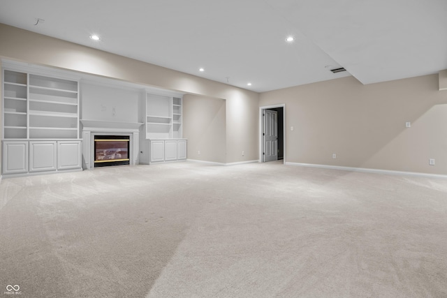 4368 W Eagle Trce, New Palestine, IN 46163 - unfurnished living room featuring baseboards, a glass covered fireplace, light colored carpet, recessed lighting, and built in shelves