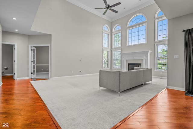 4368 W Eagle Trce, New Palestine, IN 46163 - living room featuring ornamental molding, ceiling fan, light wood-style flooring, baseboards, and a towering ceiling