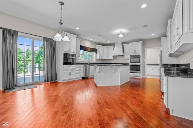 4368 W Eagle Trce, New Palestine, IN 46163 - kitchen with premium range hood, appliances with stainless steel finishes, dark countertops, light wood-style flooring, and white cabinets