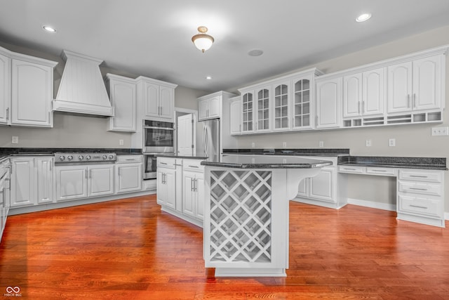4368 W Eagle Trce, New Palestine, IN 46163 - kitchen with appliances with stainless steel finishes, custom exhaust hood, white cabinetry, glass insert cabinets, and wood finished floors