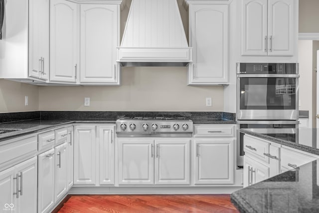 4368 W Eagle Trce, New Palestine, IN 46163 - kitchen featuring custom range hood, stainless steel appliances, white cabinetry, dark stone countertops, and wood finished floors