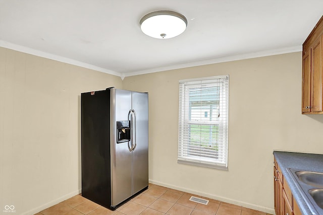 425 Aiken St, Hope, IN 47246 - kitchen with stainless steel fridge with ice dispenser, brown cabinetry, light tile patterned floors, crown molding, and dark countertops