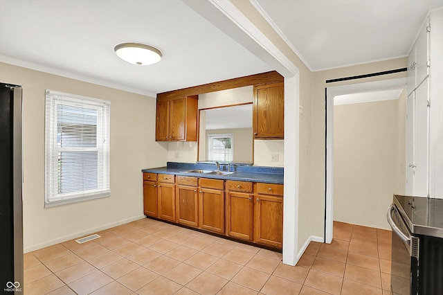 425 Aiken St, Hope, IN 47246 - kitchen with stainless steel electric range oven, brown cabinets, dark countertops, light tile patterned floors, and crown molding