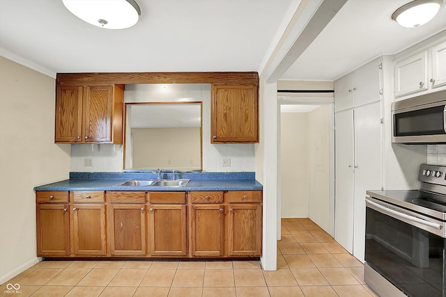 425 Aiken St, Hope, IN 47246 - kitchen with appliances with stainless steel finishes, brown cabinetry, dark countertops, and light tile patterned floors