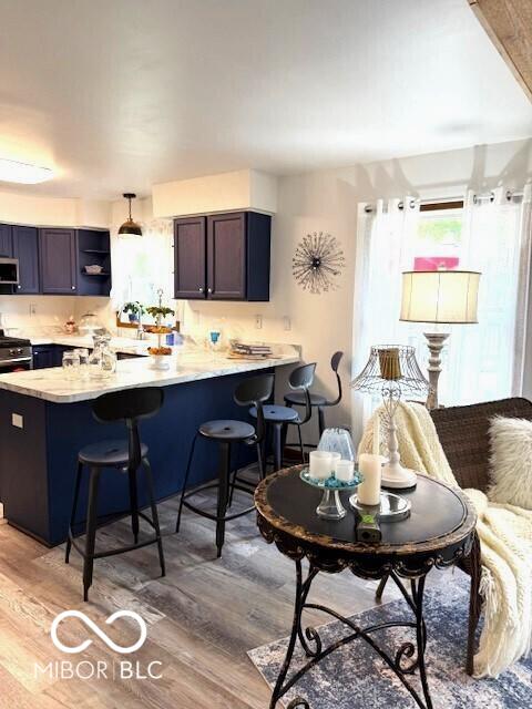 4600 S Tahoe Trl, Crawfordsville, IN 47933 - kitchen with a breakfast bar area, a peninsula, light countertops, and light wood-style flooring