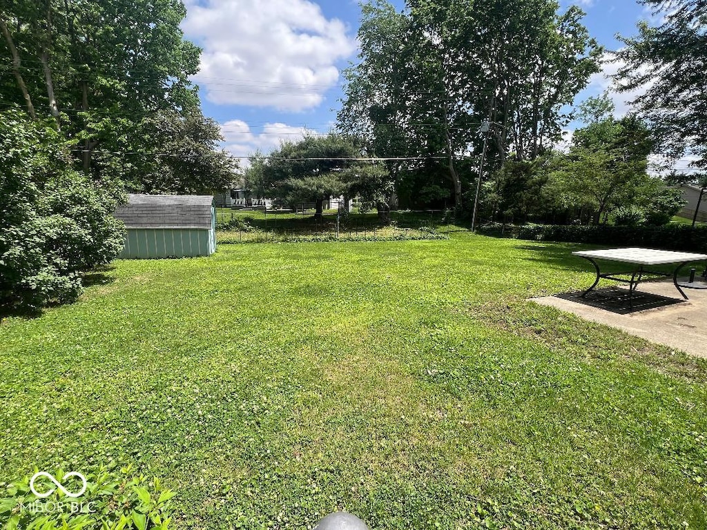 view of grassy yard featuring a storage unit and an outbuilding