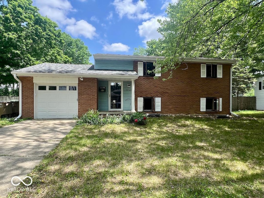 tri-level home featuring a garage, brick siding, and driveway