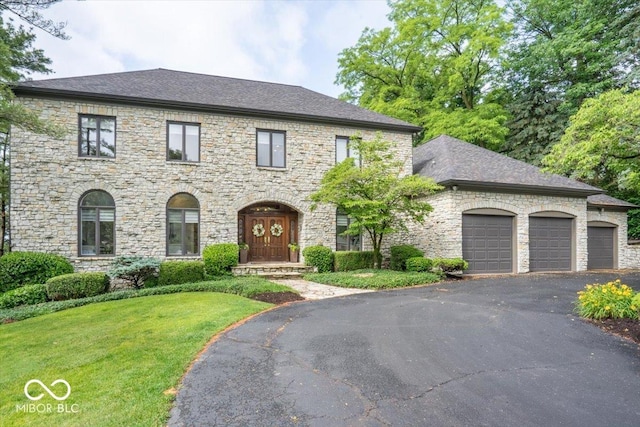 11715 Landings Dr, Indianapolis, IN 46256 - view of front of house with an attached garage, stone siding, and asphalt driveway
