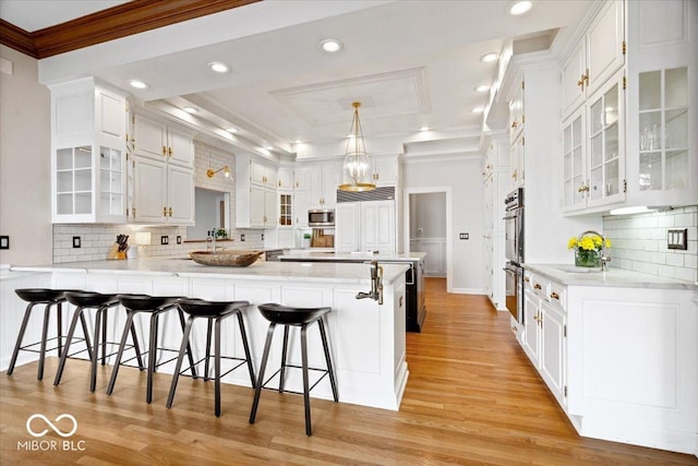 11715 Landings Dr, Indianapolis, IN 46256 - kitchen featuring a peninsula, crown molding, appliances with stainless steel finishes, white cabinets, and light wood-style flooring