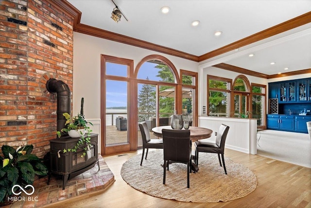 11715 Landings Dr, Indianapolis, IN 46256 - dining area with a wood stove, light wood finished floors, a wainscoted wall, crown molding, and recessed lighting