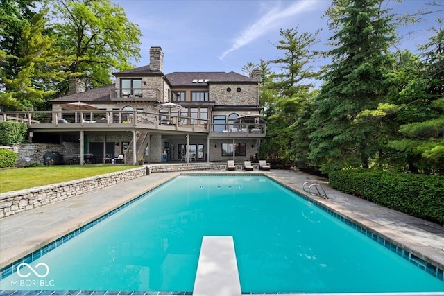 11715 Landings Dr, Indianapolis, IN 46256 - back of property featuring stone siding, a deck, a patio, an outdoor pool, and a yard