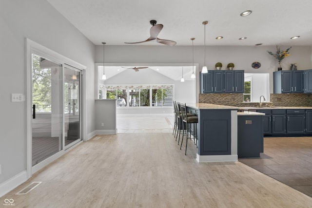 11226 Blackwalnut Pt, Indianapolis, IN 46236 - kitchen with blue cabinetry, tasteful backsplash, light countertops, a ceiling fan, and a breakfast bar
