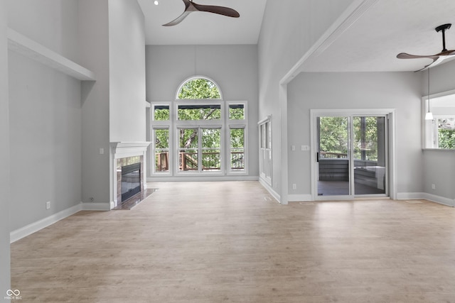 11226 Blackwalnut Pt, Indianapolis, IN 46236 - unfurnished living room featuring ceiling fan, a towering ceiling, a high end fireplace, wood finished floors, and baseboards