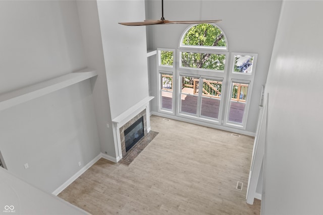 11226 Blackwalnut Pt, Indianapolis, IN 46236 - unfurnished living room featuring a ceiling fan, wood finished floors, a tile fireplace, baseboards, and a towering ceiling