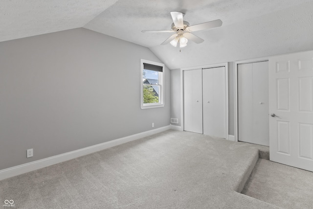 11226 Blackwalnut Pt, Indianapolis, IN 46236 - unfurnished bedroom with multiple closets, a textured ceiling, lofted ceiling, carpet flooring, and baseboards
