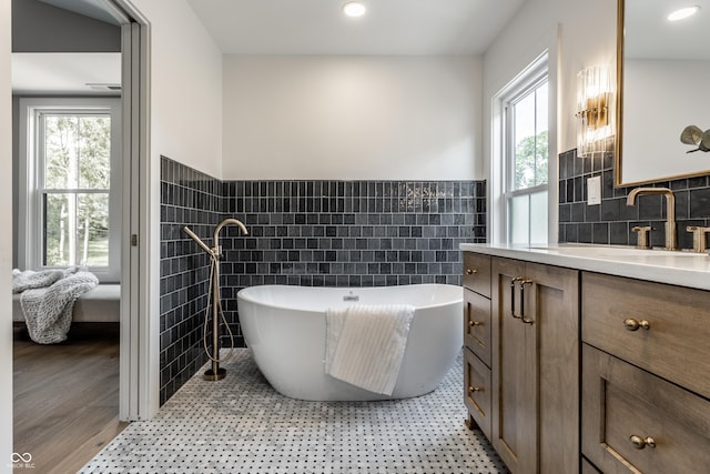 5682 Broadway St, Indianapolis, IN 46220 - bathroom with tile walls, a freestanding tub, vanity, a wainscoted wall, and recessed lighting