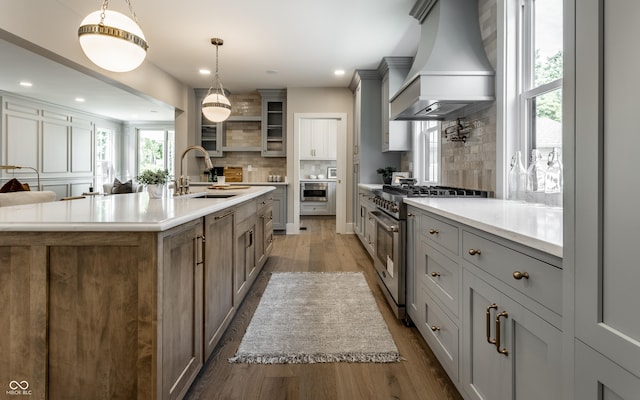 5682 Broadway St, Indianapolis, IN 46220 - kitchen with high end stainless steel range oven, a sink, premium range hood, wood finished floors, and backsplash