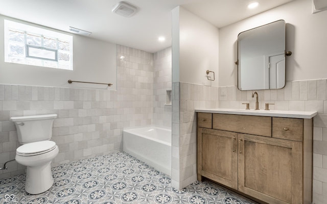5682 Broadway St, Indianapolis, IN 46220 - bathroom featuring tile walls, toilet, a bath, vanity, and a wainscoted wall