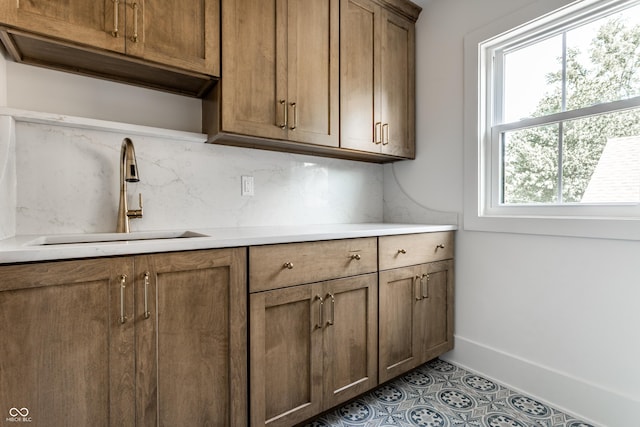 5682 Broadway St, Indianapolis, IN 46220 - kitchen featuring a sink, decorative backsplash, light countertops, and brown cabinets