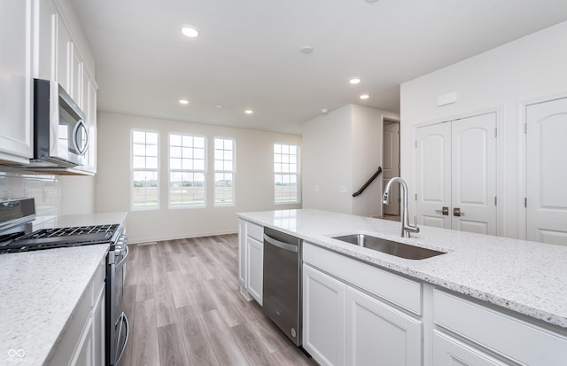 14515 Hanford Ln, Carmel, IN 46074 - kitchen with appliances with stainless steel finishes, a sink, white cabinets, light wood finished floors, and recessed lighting