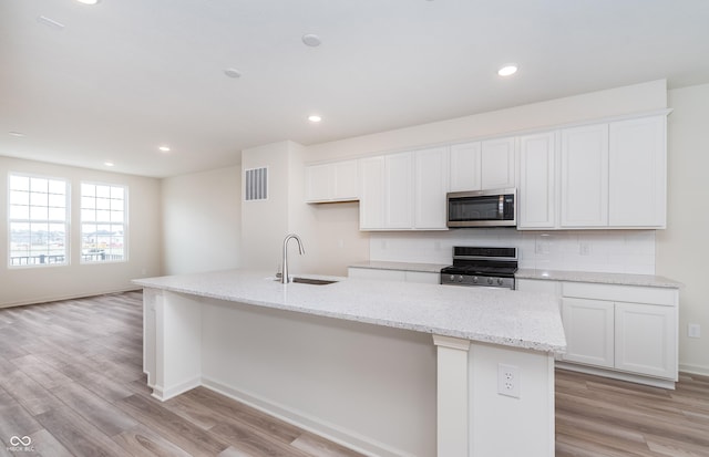 14515 Hanford Ln, Carmel, IN 46074 - kitchen featuring appliances with stainless steel finishes, a sink, an island with sink, white cabinetry, and decorative backsplash