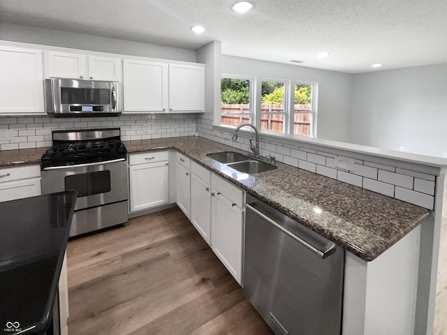 10366 Camby Xing, Fishers, IN 46038 - kitchen featuring appliances with stainless steel finishes, a sink, a peninsula, wood finished floors, and backsplash