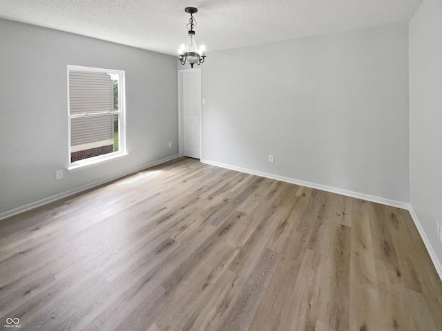 10366 Camby Xing, Fishers, IN 46038 - unfurnished room featuring a chandelier, light wood finished floors, baseboards, and a textured ceiling
