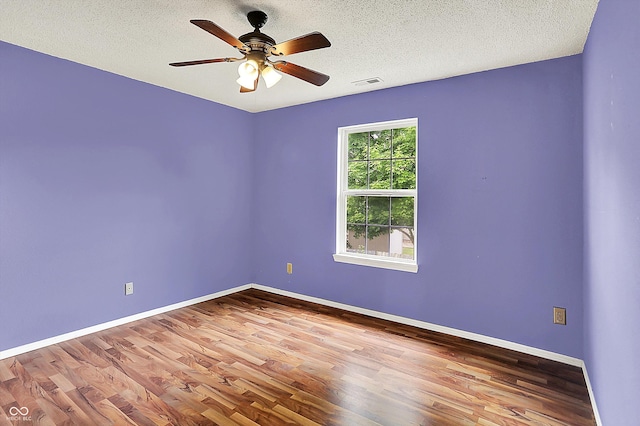 unfurnished room with wood finished floors, a textured ceiling, baseboards, and a ceiling fan