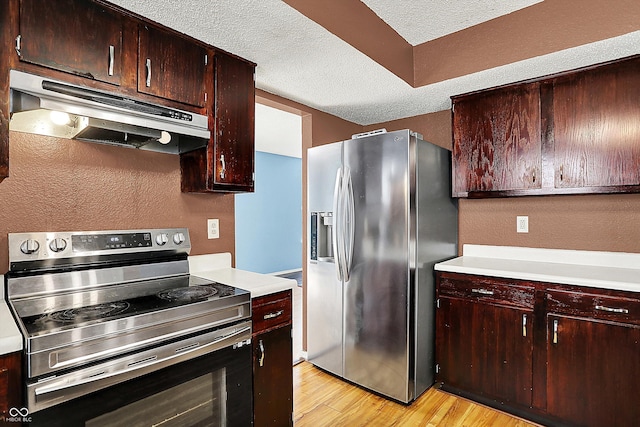 kitchen featuring stainless steel appliances, under cabinet range hood, light wood-type flooring, light countertops, and a textured wall