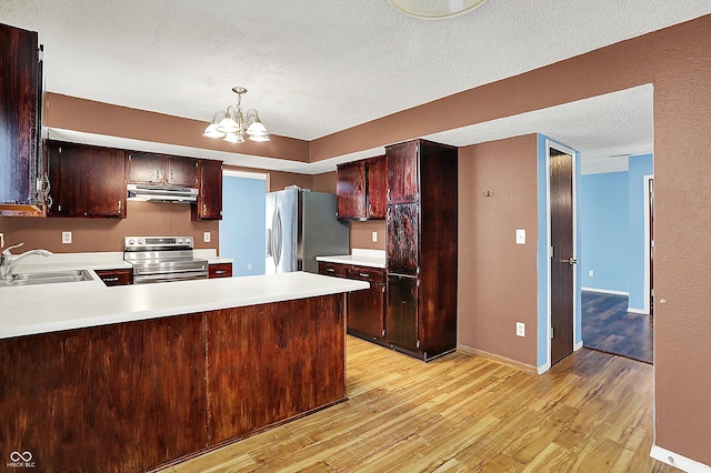 kitchen featuring appliances with stainless steel finishes, a sink, under cabinet range hood, light wood-style floors, and a textured ceiling