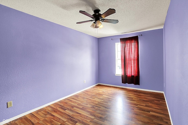 spare room with ceiling fan, a textured ceiling, wood finished floors, baseboards, and a textured wall