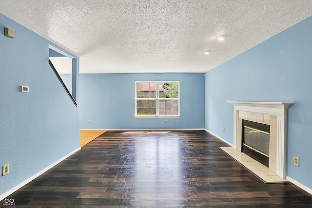 unfurnished living room with a textured ceiling, hardwood / wood-style floors, a fireplace, and baseboards