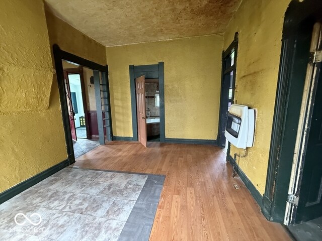 105 N Sheridan St, Ridgeville, IN 47380 - empty room with a textured wall, heating unit, wood finished floors, and baseboards