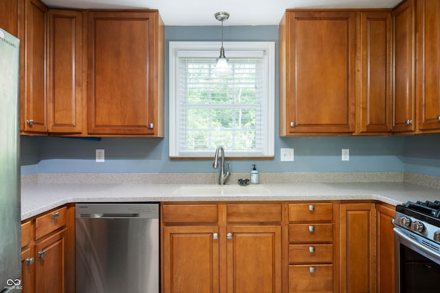 7910 N College Ave, Indianapolis, IN 46240 - kitchen with stainless steel appliances, a sink, brown cabinets, light countertops, and decorative light fixtures