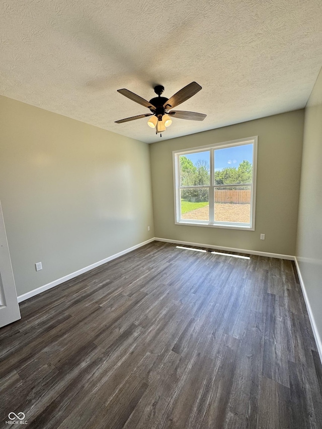 unfurnished room with dark wood-type flooring, baseboards, a ceiling fan, and a textured ceiling