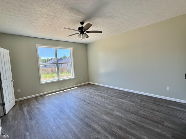 spare room featuring dark wood-type flooring, a ceiling fan, baseboards, and a textured ceiling
