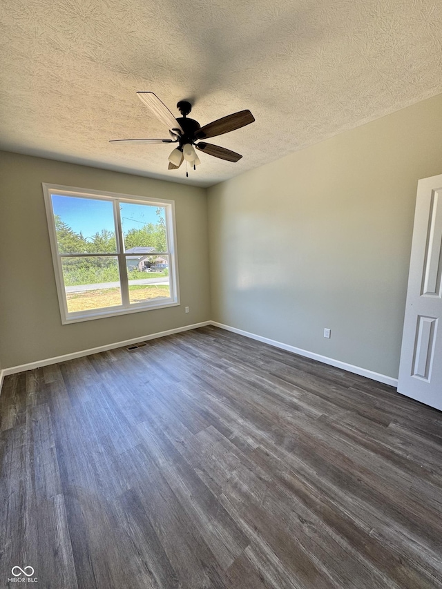 unfurnished room with dark wood-style floors, ceiling fan, baseboards, and a textured ceiling